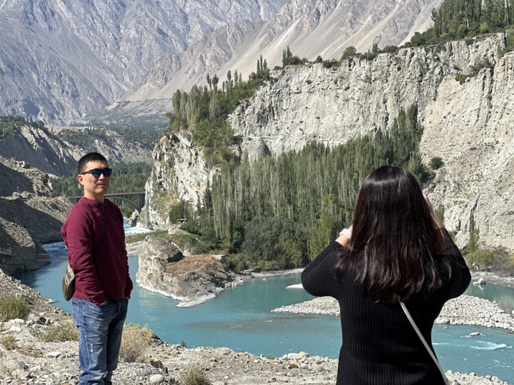 Two travellers beside a turquoise mountain lake