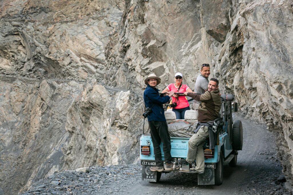 Guests beside a blue jeep on a mountain track