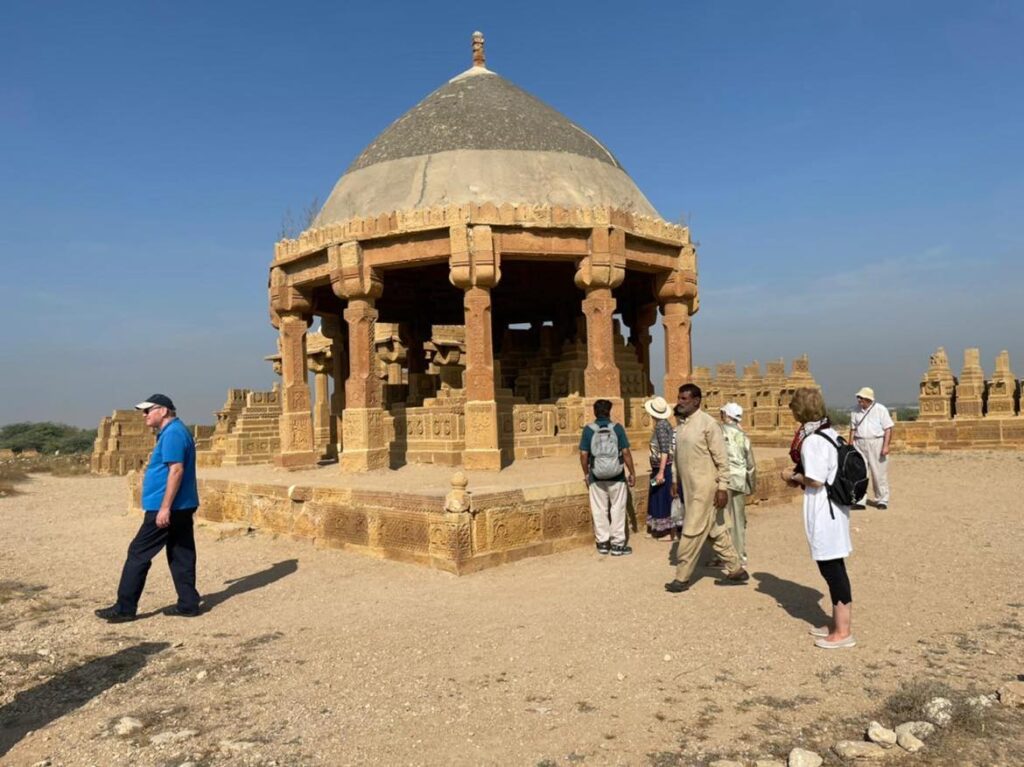Guests beside a stone pavilion at Makli