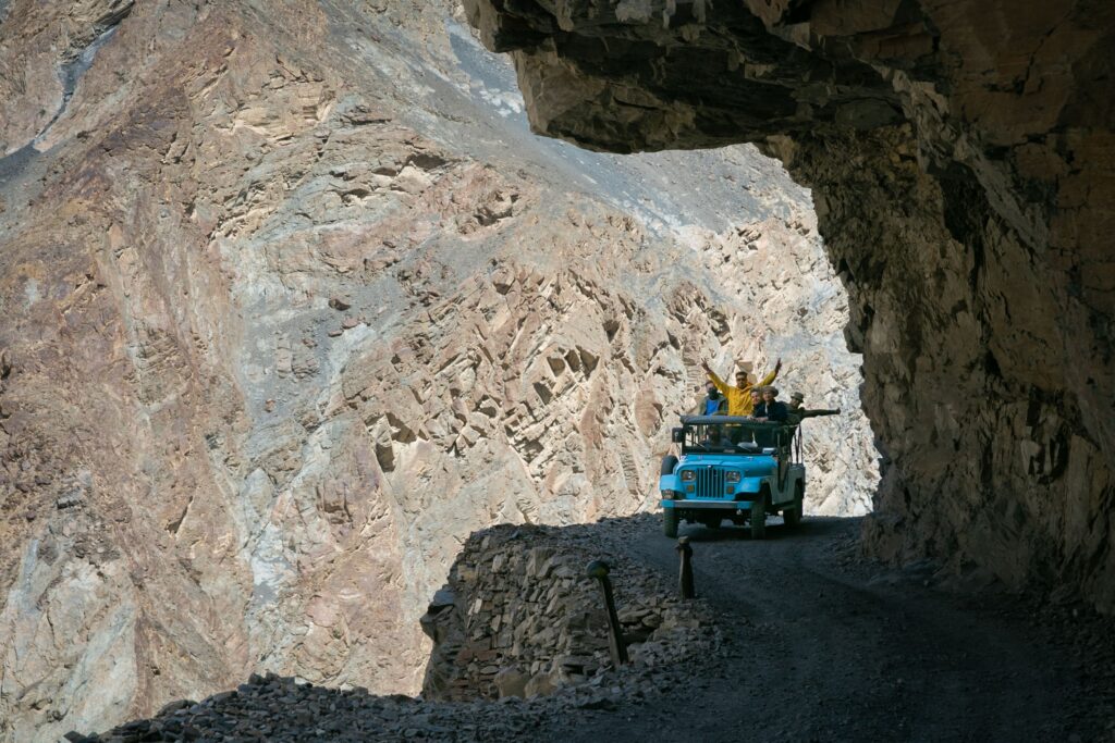 Blue jeep following a narrow cliffside road