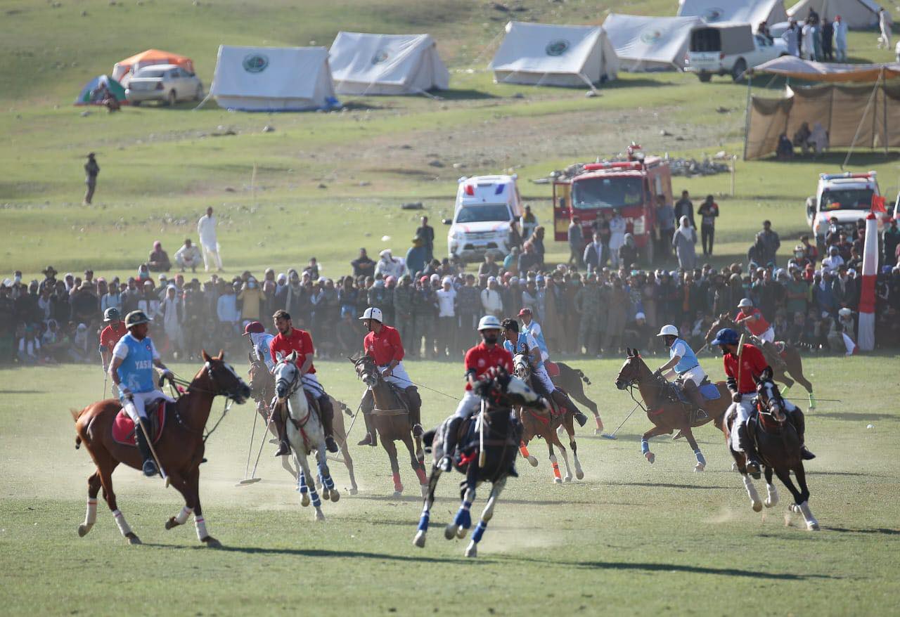 Mounted polo players in front of spectators and temporary tents at Shandur
