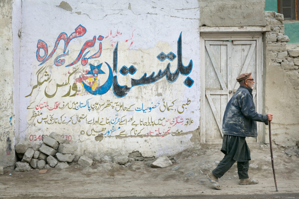 A resident beside a painted wall and doorway in Shigar, Baltistan.