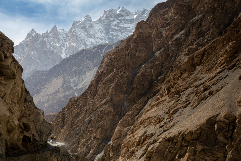 Rocky mountain gorge and distant snow-covered peaks on the road to Shimshal Valley.