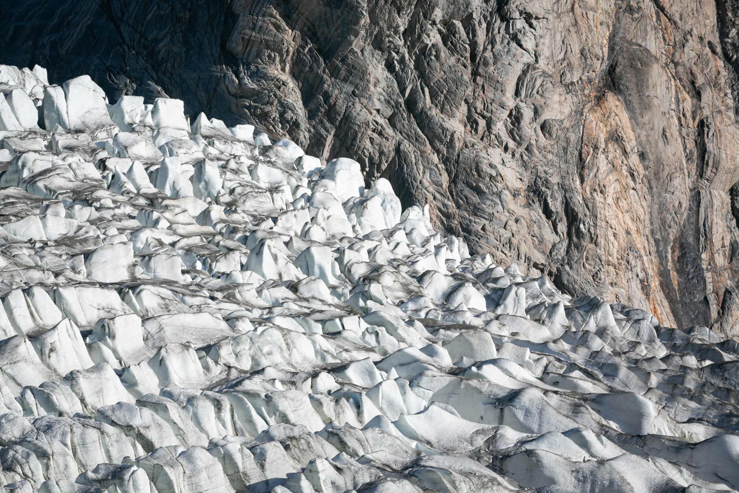 Jagged glacier ice beneath the rocky mountain walls near Passu, Upper Hunza.