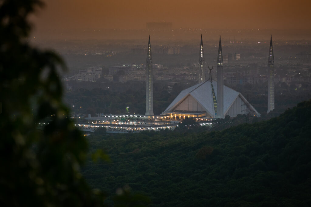 Faisal Mosque and its slender minarets overlooking Islamabad as evening settles over the city.