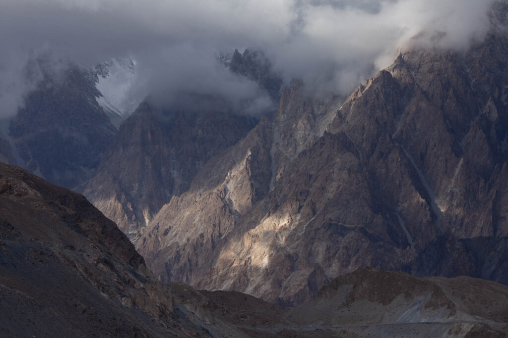 Clouds gathering around steep, jagged mountain peaks in northern Pakistan.