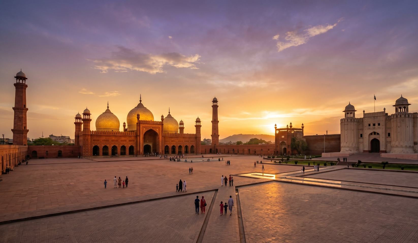 Badshahi Mosque and Lahore Fort viewed together at sunset in Lahore Pakistan with the mosque minarets glowing red and gold against a purple sky