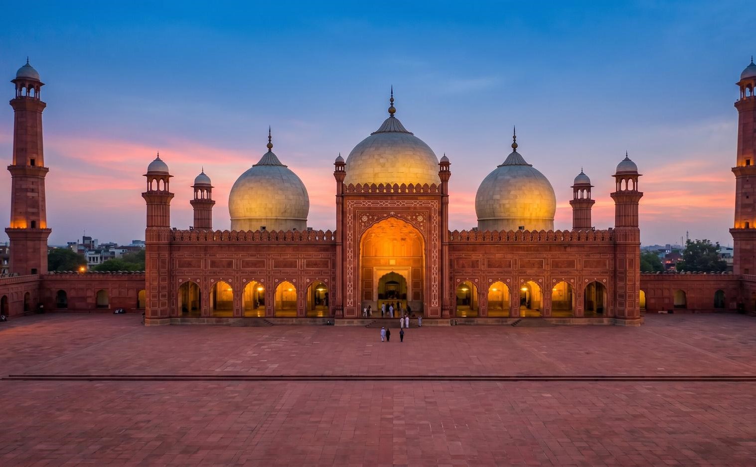 Badshahi Mosque Lahore Pakistan at sunset with red sandstone and white marble glowing against a deep blue sky