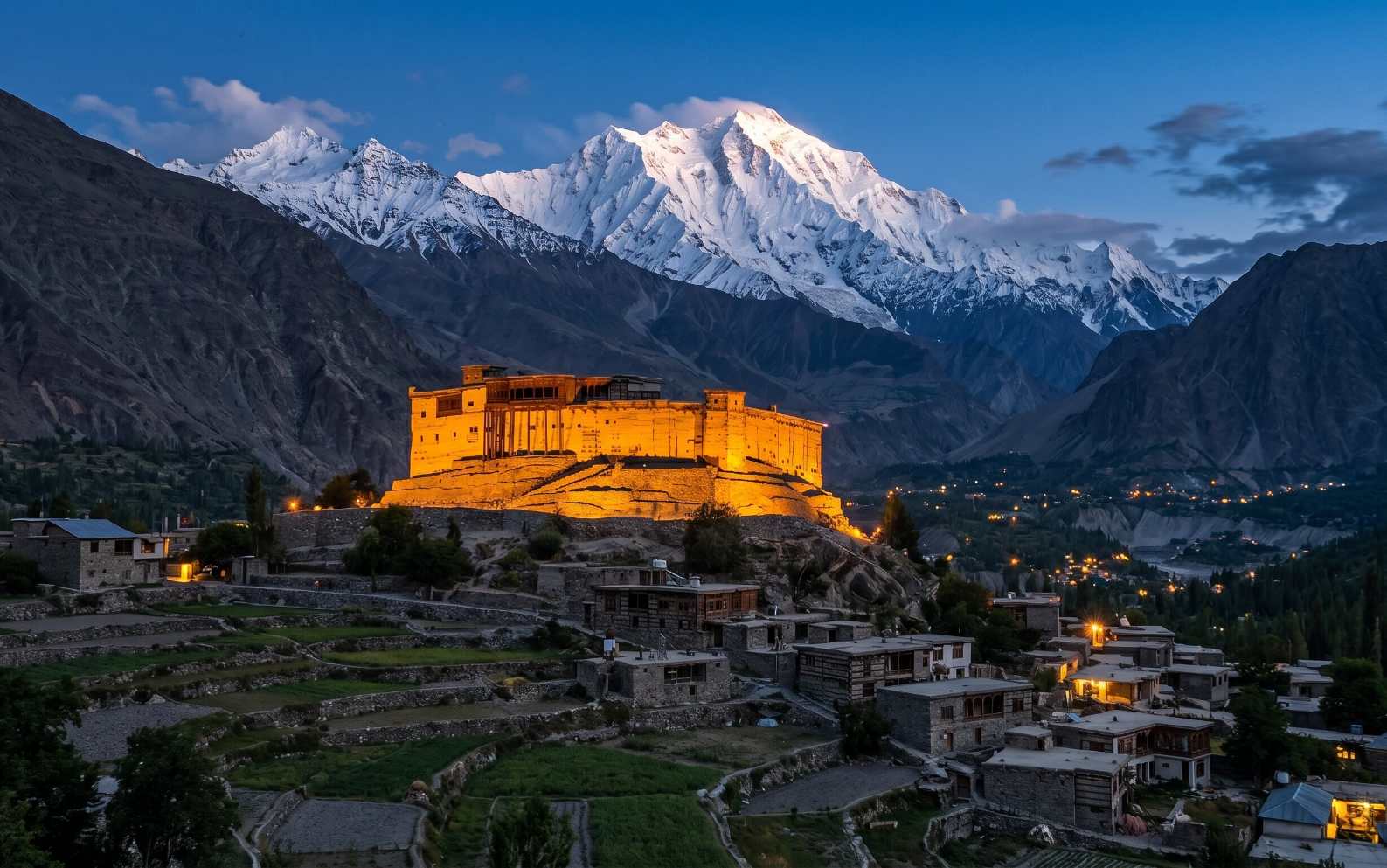 Baltit Fort in Karimabad Hunza Pakistan at dusk with Rakaposhi mountain rising snow-covered behind the ancient multi-storey stone and timber fortress