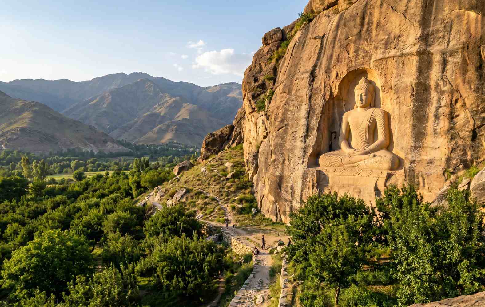 The Jahanabad Giant Buddha rock carving in Swat Valley Pakistan carved into a cliff face surrounded by orchard trees