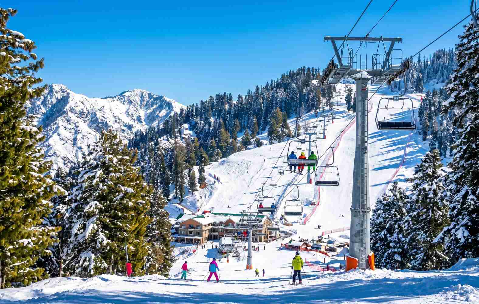 Malam Jabba ski resort in Swat Pakistan in winter with snow-covered slopes, pine trees and the chairlift against a blue sky