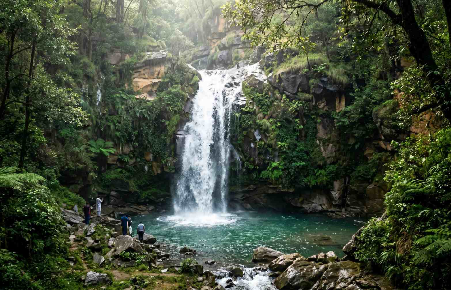 Shingrai Waterfall in Swat Valley Pakistan cascading down dark rocks surrounded by lush green vegetation