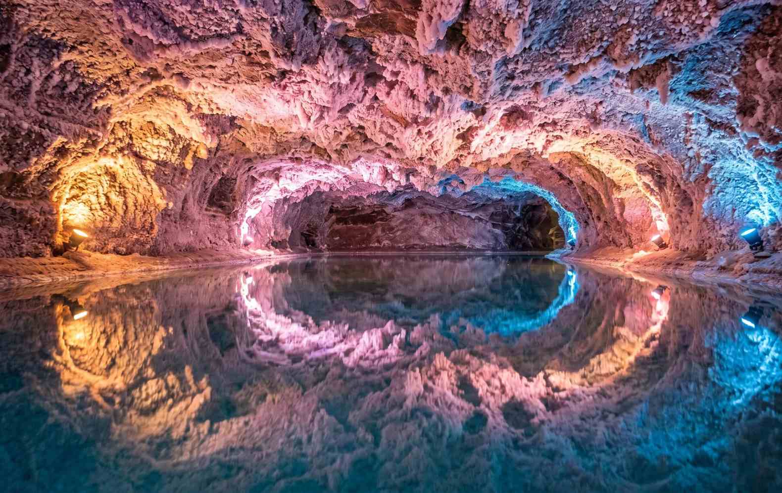 Underground brine pool inside Khewra Salt Mine Pakistan with pink salt ceiling perfectly reflected in the still hypersaline water