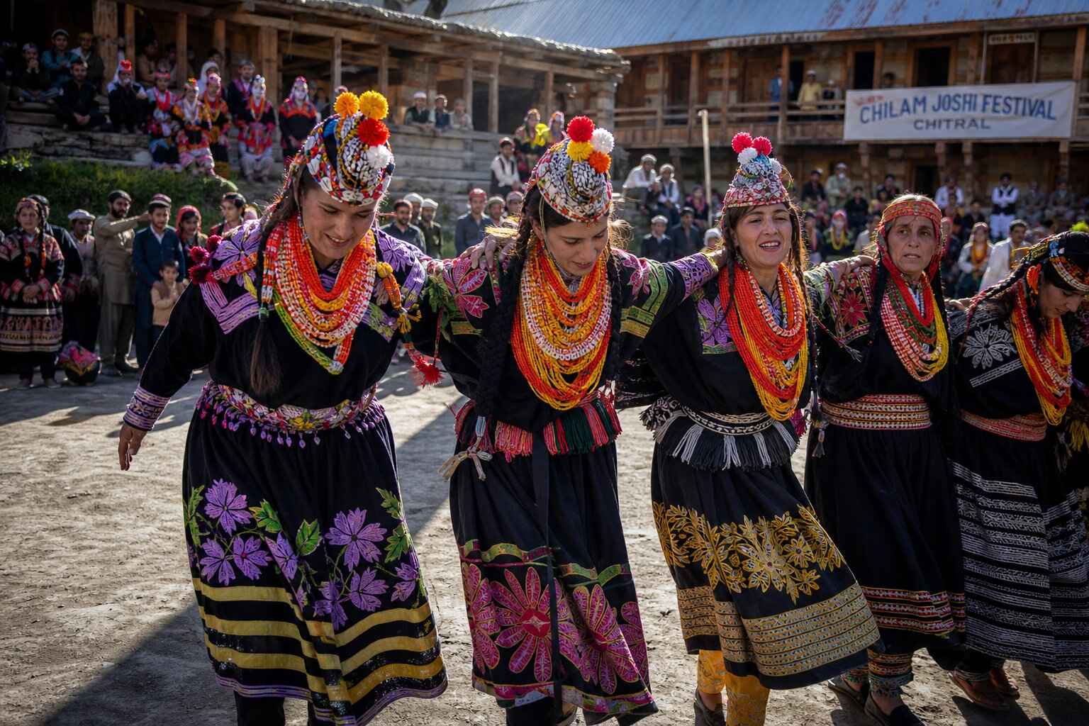 Kalash women in traditional colourful embroidered dress and beaded headdresses dancing at the Chilam Joshi spring festival in Chitral Pakistan
