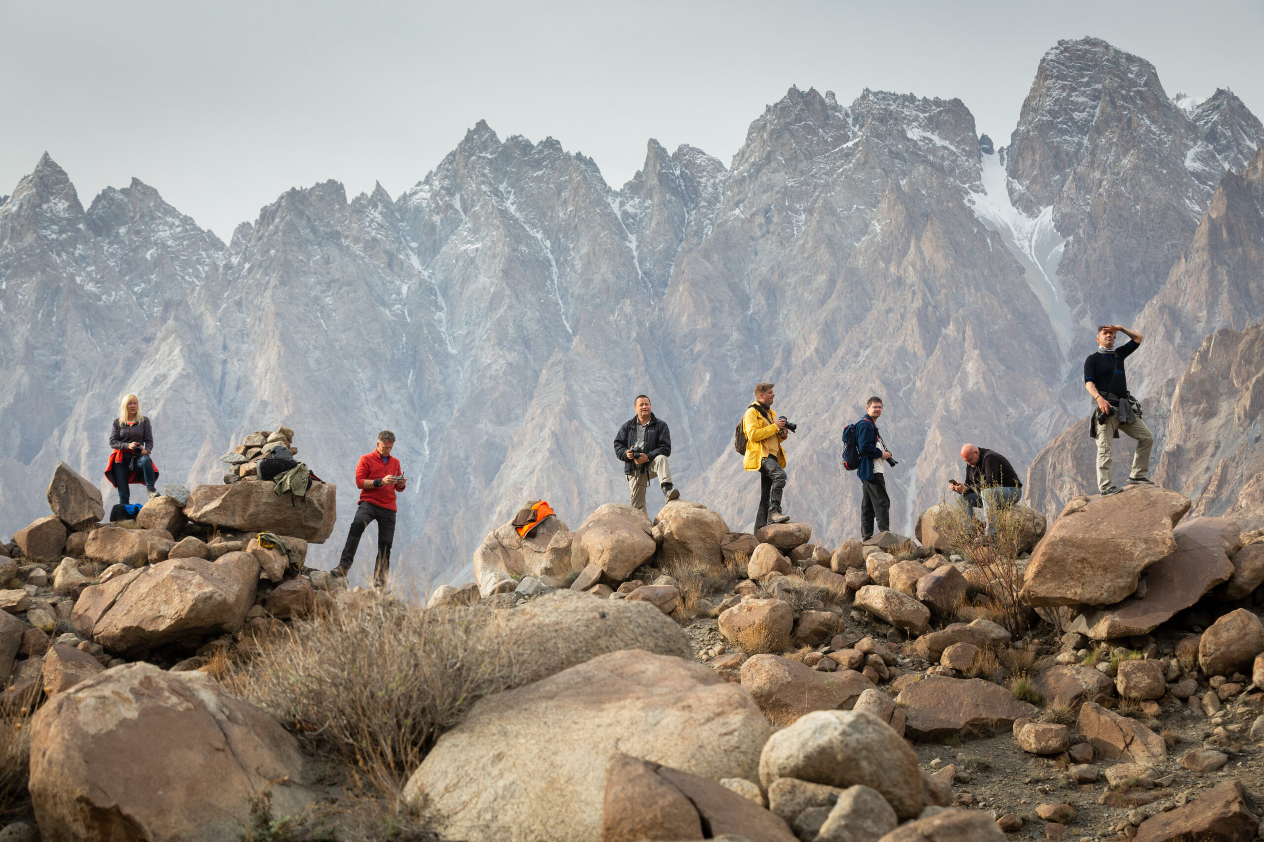 Travellers with cameras beneath mountain peaks in Pakistan