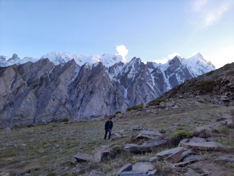 Trekker on the rocky Patundas pasture with snow-covered Karakoram peaks behind